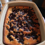 Golden-brown berry cobbler cake with a crispy sugar topping, bubbling with vibrant blueberries and raspberries.